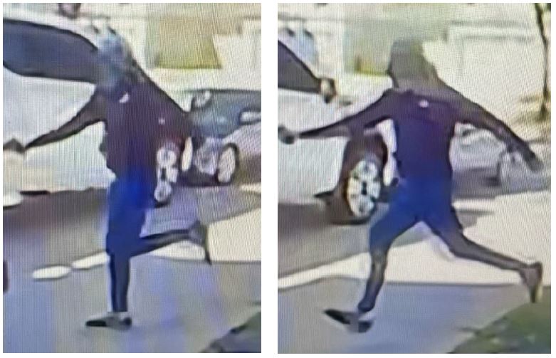 Camera footage screenshot of the suspect running across a sidewalk wearing a hooded ball cap, dark shirt and bright blue shorts. 